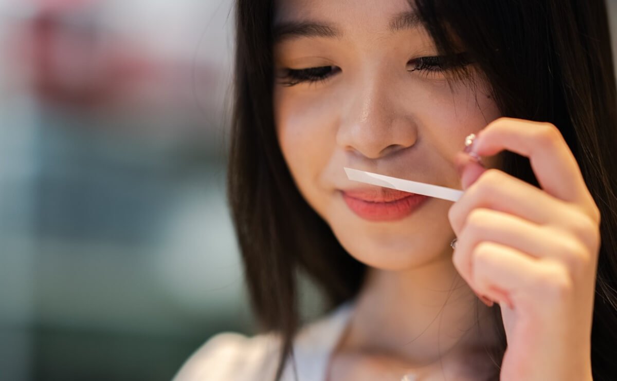 woman holding paper scent strip and enjoying the scent