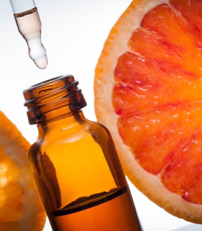 close up of essential oil bottle and orange slice