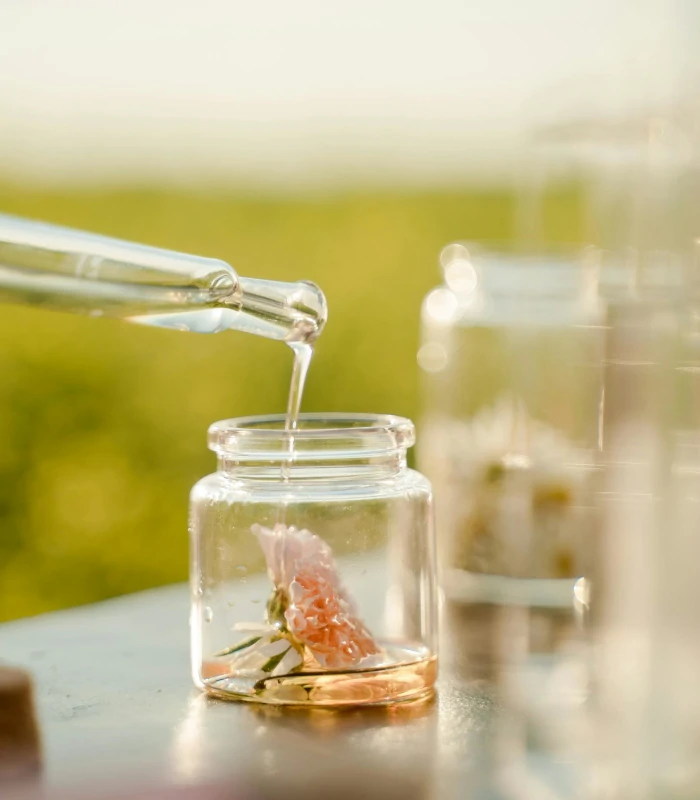 dropper with essential oil dripping into glass bottle