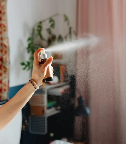 female hand holds a bottle of aroma spray sending out mist