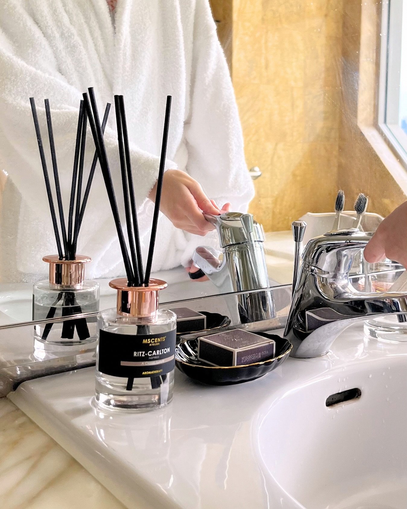 A person by the sink cleaning hands beside aromatherapy oil