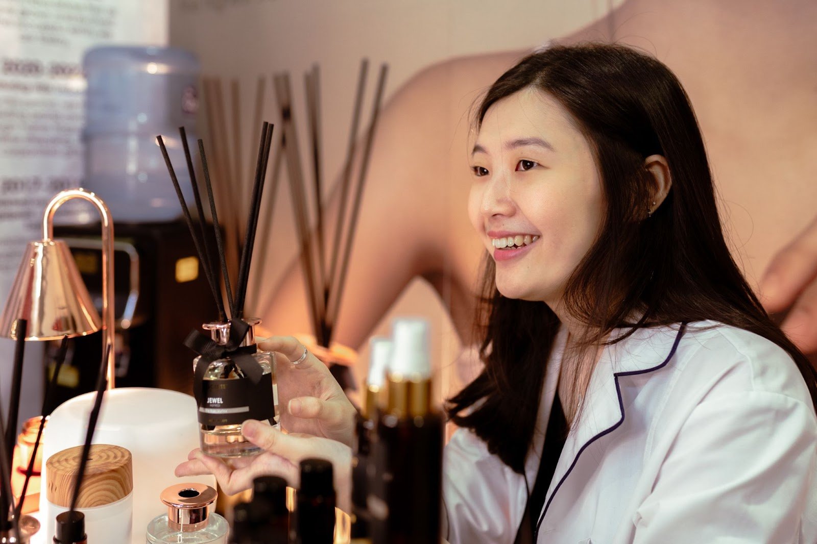 A smiling young woman holding a reed diffuser