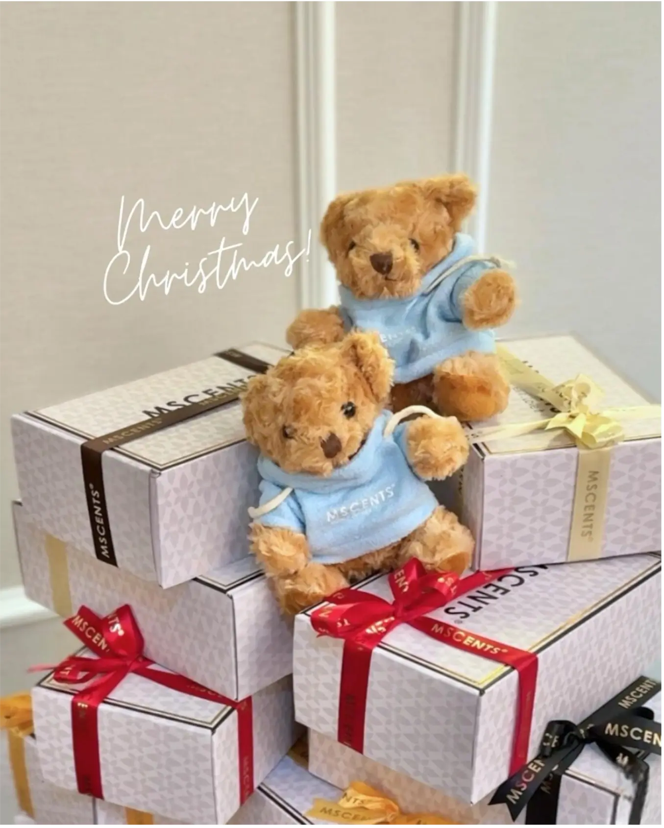 2 small teddy bears sit on top a heap of MScents gift boxes