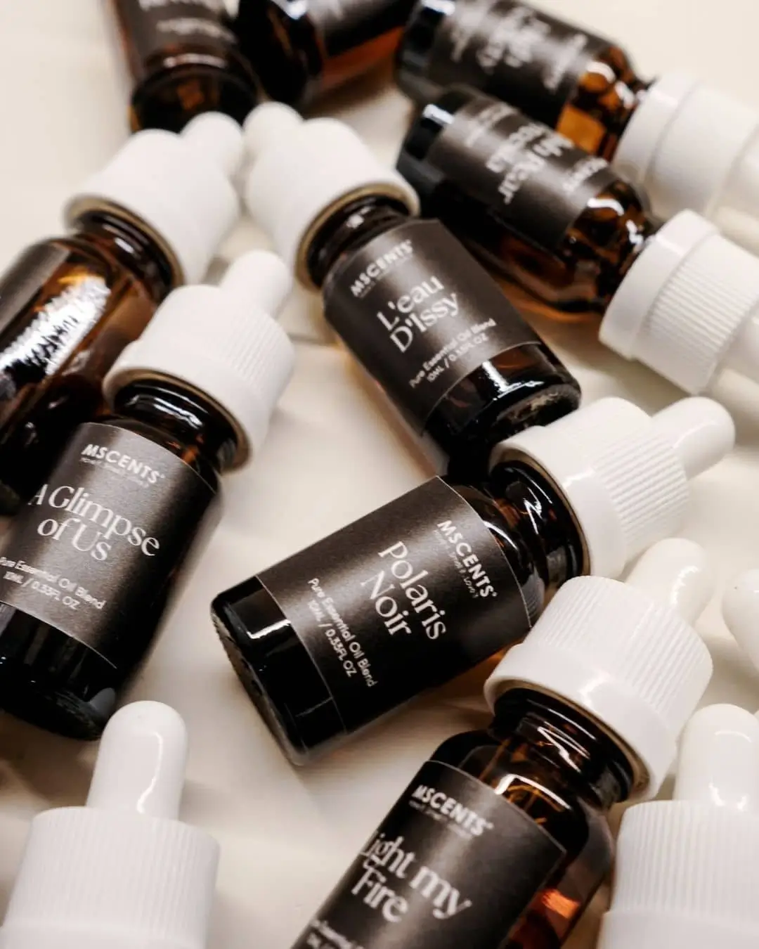 Bottles of MScents luxury perfume collection pure essential oil scattered over white cloth