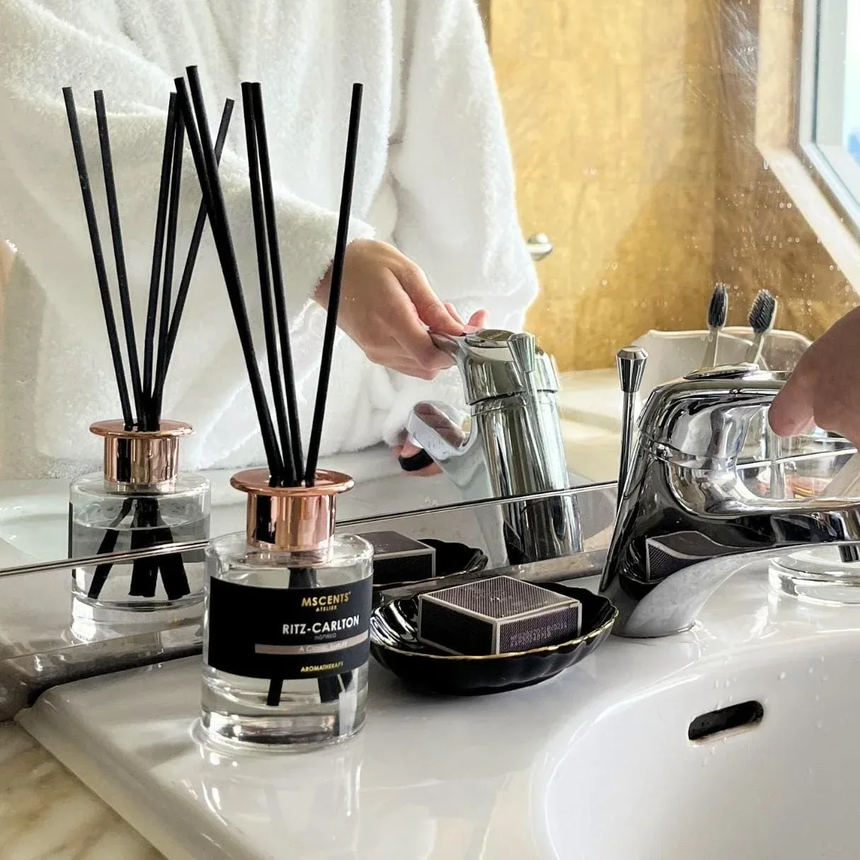 A person by the sink cleaning hands beside aromatherapy oil