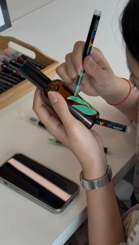 A woman painting her bottle for her custom perfume