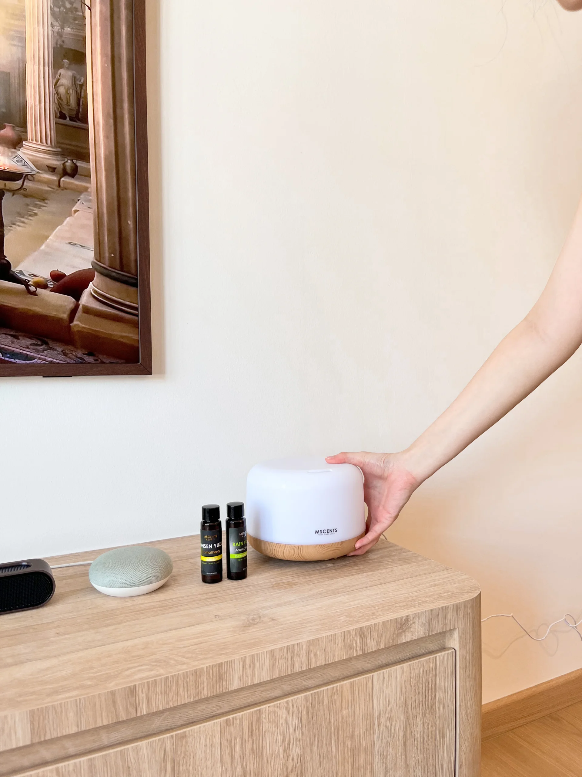 A-hand-placing-a-scent-diffuser-on-top-of-a-room-table